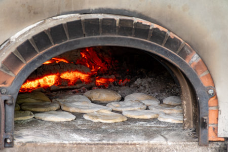 Baking of flat pita bread in wood-fired oven on local street marketの写真素材