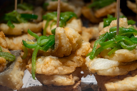 Typical snacks of Basque Country, pinchos or pinxtos skewers with small pieces of bread, fish, sea food, sweet green pepper served in bar in San-Sebastian or Bilbao, Spain, close upの写真素材
