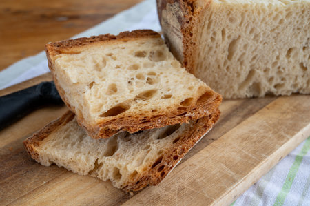 Freshly baked big sourdough traditional Italian wheat bread on olive wood fired oven in pieces
