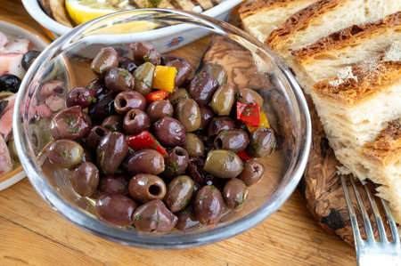 Pickled olives, grilled eggplant, octopus seafood salad, artichokes, vegetables on wooden table, variety of tasty starters, antipasti, top viewの写真素材