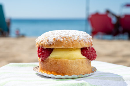 Lunch on sandy beach in Saint-Tropez with cake Tarte tropezienne filled brioche with cream and fresh red berries, summer vacation on sunny French Riviera, Franceの写真素材