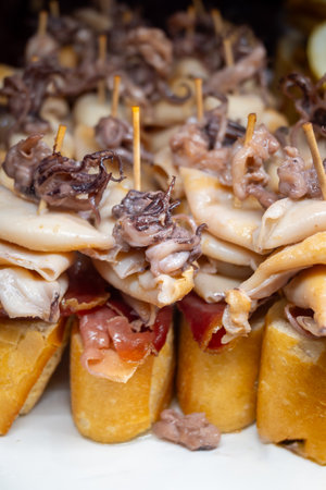 Typical snacks of Basque Country, pinchos or pinxtos skewers with small pieces of bread, fish, sea food, sweet green pepper served in bar in San-Sebastian or Bilbao, Spain, close upの写真素材