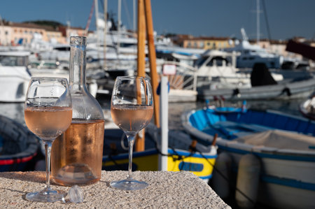 Glasses of cold french rose Cote de Provence wine in old fisherman boats port and yachts harbor in Saint-Tropez, summer vacation on French Riviera in Provence, Franceの写真素材