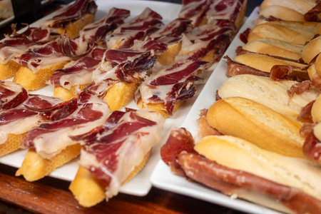 Typical snacks of Basque Country, pinchos or pinxtos skewers with small pieces of bread, fish, sea food, sweet green pepper served in bar in San-Sebastian or Bilbao, Spain, close upの写真素材