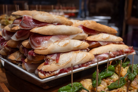 Typical snacks of Basque Country, pinchos or pinxtos skewers with small pieces of bread, fish, sea food, sweet green pepper served in bar in San-Sebastian or Bilbao, Spain, close upの写真素材