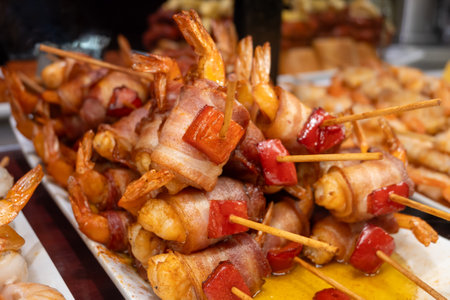 Typical snacks of Basque Country, pinchos or pinxtos skewers with small pieces of bread, fish, sea food, sweet green pepper served in bar in San-Sebastian or Bilbao, Spain, close upの写真素材