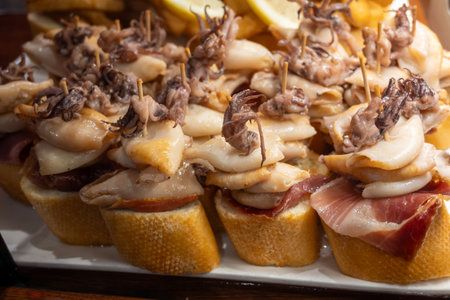 Typical snacks of Basque Country, pinchos or pinxtos skewers with small pieces of bread, fish, sea food, sweet green pepper served in bar in San-Sebastian or Bilbao, Spain, close upの写真素材