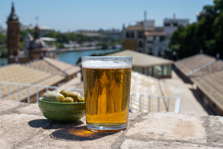 Beer, cheese, tapas and green andalusian olives served on outdoor roof terrace with view on central part of old Sevilla, Andalusia, Spain in summerの写真素材