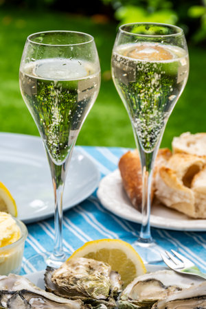 Champagne sparkling wine in glasses and oysters molluscs from Arcachon bay served on oysters farm in Gujan-Mestras, with lemon, baquette bread, butterの写真素材