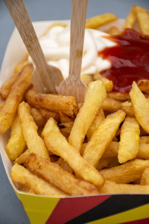 Belgian street and fast food, paper box in colors of Belgian flag with fried potato frit chips and ketchup and mayonnaise sauÑe, Brussels, Belgiumの写真素材