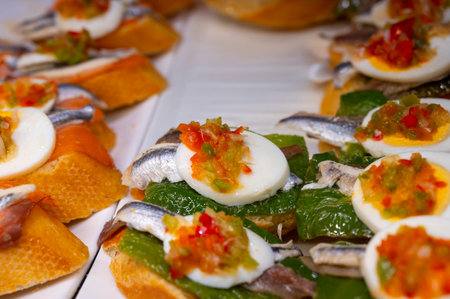 Typical snack of Basque Country, pinchos or pinxtos skewers with small pieces of bread, sea food, eggs, cheese, jamon served in bars in San-Sebastian or Bilbao, Spain, close upの写真素材
