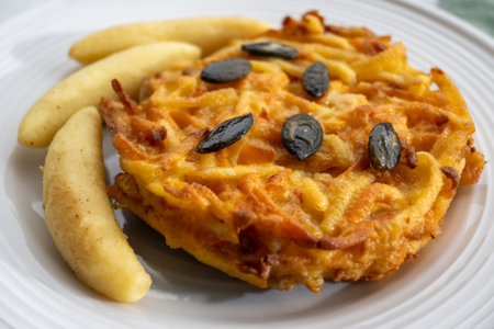 Pumpkin grated roasted patties, rosti or latkes and Fingernudel, finger potato noodle, dumplings decorated with pumpkin seeds close upの写真素材