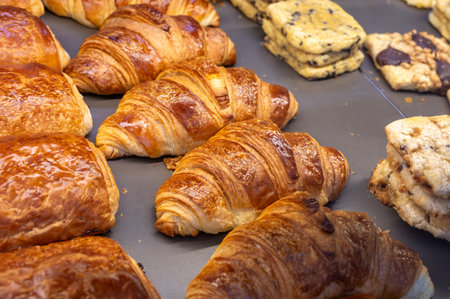 Fresh baked buttered croissants and sweet buns, pastries in village bakery early morning in France