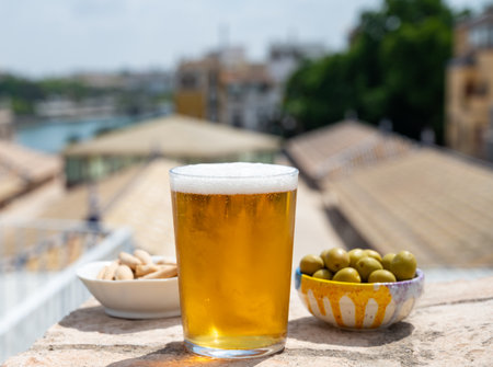 Lager beer in glasses and bowl with green andalusian olives served on outdoor roof terrace with view on central part of old Sevilla, Andalusia, Spainの写真素材