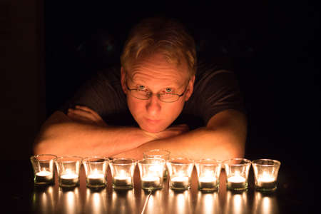 Candles lighting the face of a handsome man.の写真素材