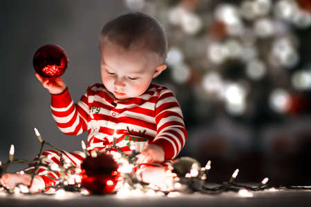 Cute infant playing with Christmas lights and decorations.の写真素材