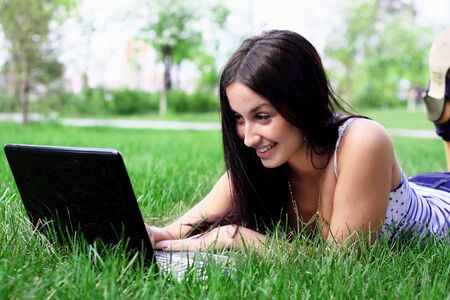 Charming brunette with a laptop in the summer meadow の写真素材