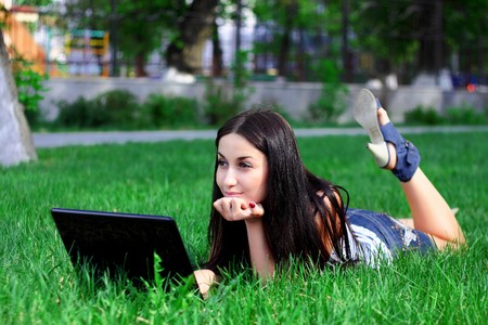Charming brunette with a laptop in the summer meadowの写真素材