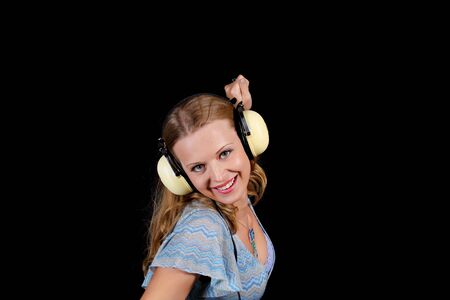 a charming young blonde on a black background with earphonesの写真素材