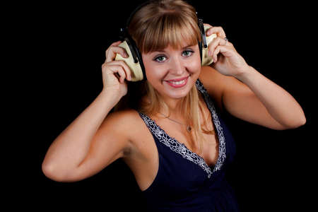 a charming young blonde on a black background with earphonesの写真素材