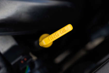 Yellow oil dipstick in a car engine. Measuring the engine oil level. Oil dipstick for checking the engine oil level in the engine system.の写真素材