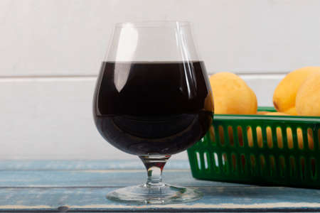 A set of a glass with red wine and peaches. A glass of red wine.