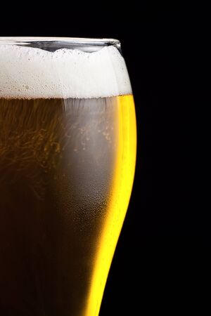Part of a glass of cold beer is a light froth.の写真素材