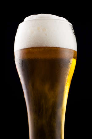 Part of a glass of cold beer is a light froth.の写真素材
