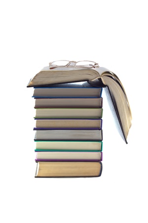 A stack of books on top of an open book and glasses all isolated on a white background.の写真素材