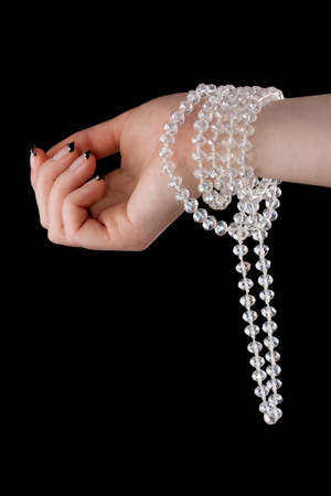 Shiny necklace in a beautiful female hand on a black background の写真素材