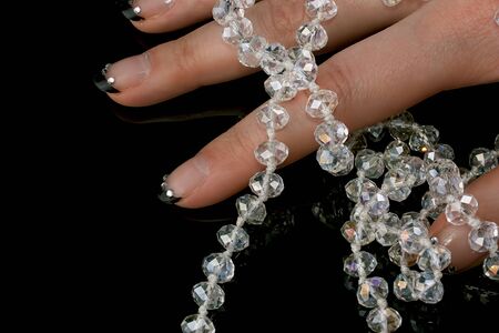 Shiny necklace in a beautiful female hand on a black background の写真素材
