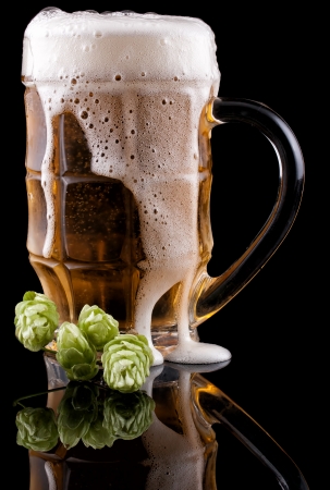 Glass of cold beer on a black background  Nearby lies hop の写真素材