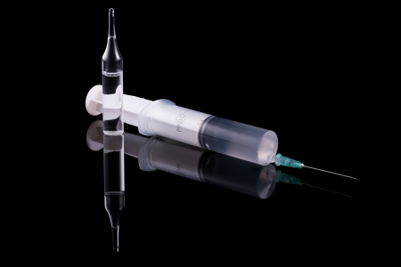 Medical syringe and glass vial on a black background の写真素材