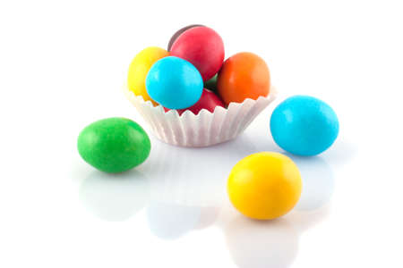 Multicolored round candies in paper basket on a white background  の写真素材
