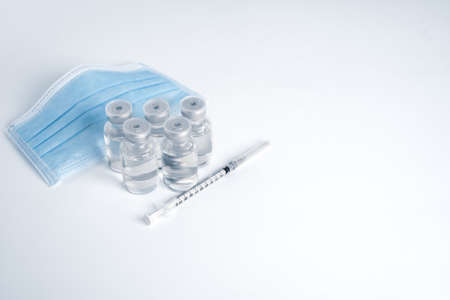 Empty bottle of vaccine with syringe and mask for hygiene injection.