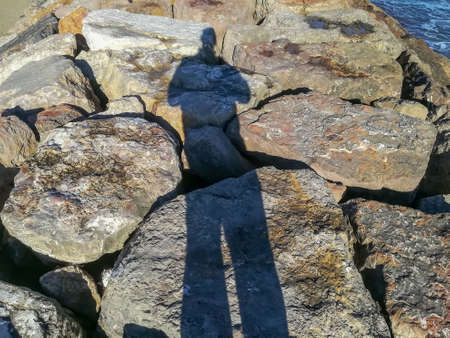 Shadow of spiky person on a breakwater in the Mediterranean Seaの写真素材