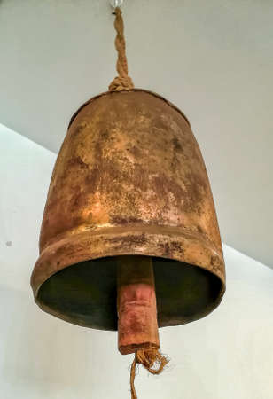 Old and rusty metal cowbell hanging from the ceiling
