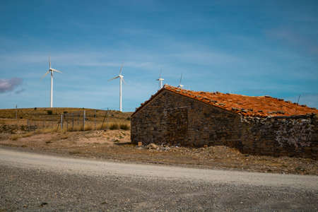 Old abandoned stone house with windmills in the background