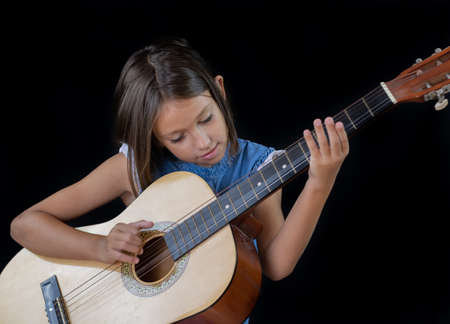 Small girl playing guitar on black backgroundの写真素材
