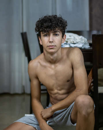 Young boy posing without shirt in the living room at homeの写真素材