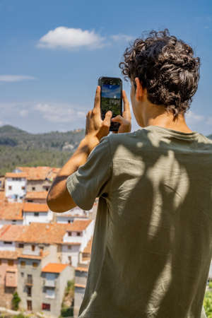 Young man photographing a mountain townの写真素材