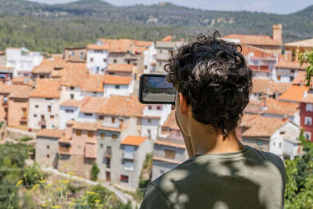 Young man photographing a mountain townの写真素材