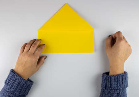 Woman folding a piece of paper on gray backgroundの写真素材