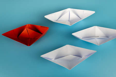Red origami paper boat on blue background