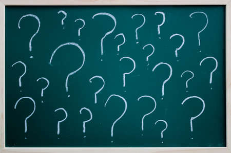 Questions marks written on a blackboard with white chalk