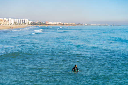Men surfing in the Mediterranean Sea next to the breakwater