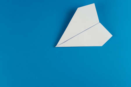 Handmade white paper plane on blue background in travel conceptの写真素材