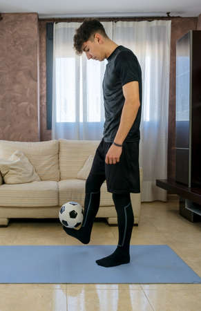 Young man with black sportswear practicing exercise in the living room at home on blue mat