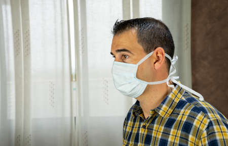 Man posing with mask in the living room of his house protecting himself from the covid-19