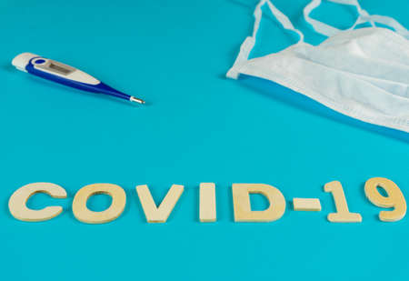 Medical equipment with mask and covid-19 thermometer on blue backgroundの写真素材